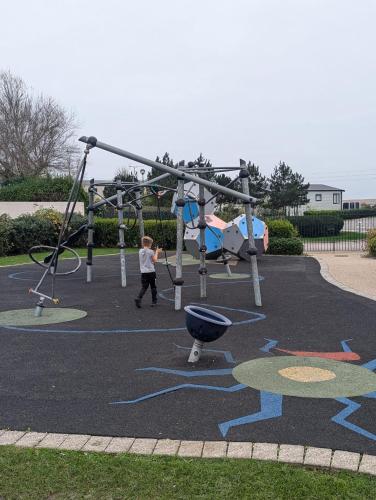 a boy playing on a playground in a park at STYLISH HOLIDAY HOME WITH UNINTERRUPTED VIEWS OF THE FLEET LAGOON ON Haven LITTLESEA HOLIDAY PARK in Wyke Regis