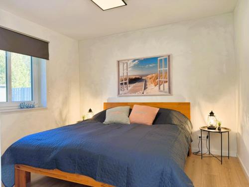 a bedroom with a blue bed and two windows at Fördezauber - Ruhiges Ferienhaus mit eingezäuntem Garten und Kamin in Bönstrup