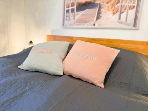 two pillows sitting on top of a bed at Fördezauber - Ruhiges Ferienhaus mit eingezäuntem Garten und Kamin in Bönstrup