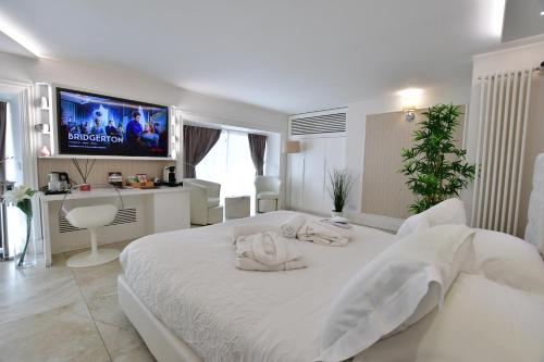 a white bedroom with a large bed and a tv at Domus De Cinti in Tivoli