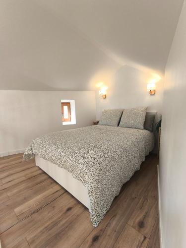 a bedroom with a bed and a wooden floor at Gîte de la Cheminée in Saint-Privat