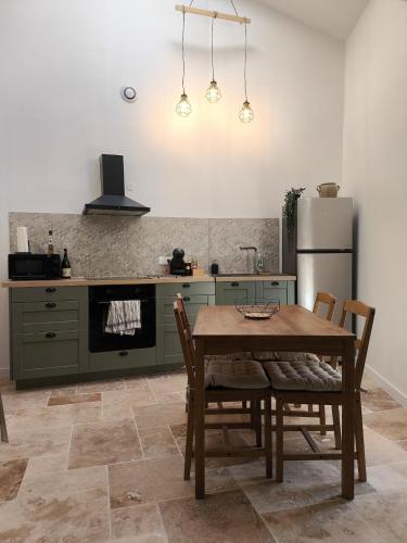 a kitchen with a wooden table and a refrigerator at Gîte de la Cheminée in Saint-Privat