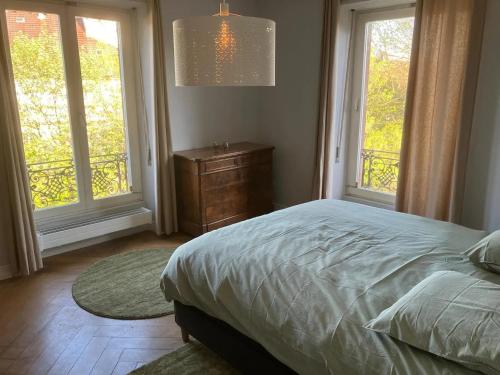 une chambre avec un lit et une commode et deux fenêtres dans l'établissement Magnifique Manoir proche Strasbourg et Europa Park, à Sand