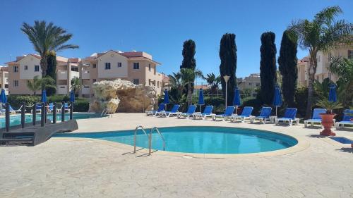 a swimming pool with blue chairs and palm trees at Pyla Village Resort E108 in Pyla