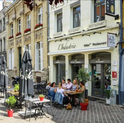 a group of people sitting at tables outside a restaurant at Hôtel Restaurant L'Industrie in Saint-Omer