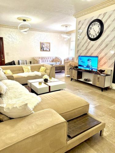 a living room with a couch and a clock on the wall at Stylish 3 Bedroom apartment in Amman in Amman