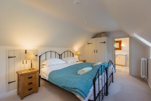 a bedroom with a large bed with a blue comforter at The Coach House at Noelle's Cottages in Pickering