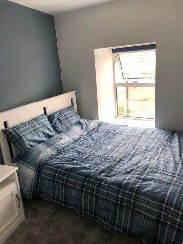 una camera da letto con un letto con una coperta blu e una finestra di Contemporary Town Centre on the Wild Atlantic Way a Bantry