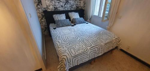 - un lit avec une couette et des oreillers en noir et blanc dans l'établissement Maison Cosy Intra-muros, clim, parking, extérieur, à Aigues-Mortes