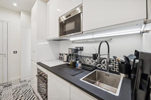 a white kitchen with a sink and a microwave at La Maison Kléber - Luxury apartments, Champs-Elysées - Eiffel Tower in Paris