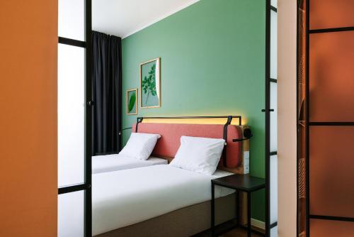 a bedroom with a bed with white sheets and green walls at Hotel Convictus Cracovia for business & travellers in Kraków