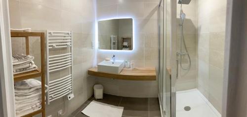 une salle de bain blanche avec un lavabo et une douche dans l'établissement Les portes du soleil, à Les Sables-dʼOlonne