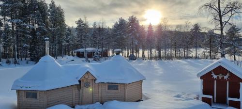 a house in the snow with the sun in the background at Wild Power Guesthouse in Lycksele