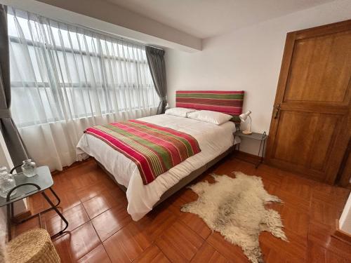 a bedroom with a bed and a window and a rug at La Maison Samaï in Urubamba