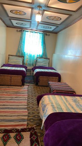 a room with four beds in a room with a window at Kasbah Ait Bouguemez in Agouti