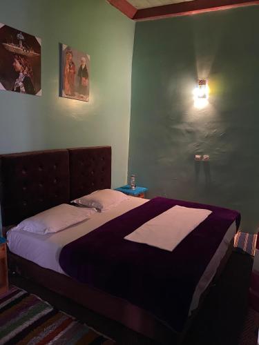 a bedroom with a large bed with a purple blanket at Kasbah Ait Bouguemez in Agouti