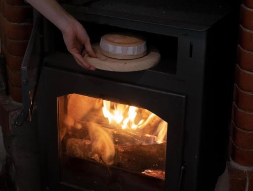 een persoon die een pizza in een open haard stopt bij Villa del Jerte in El Torno