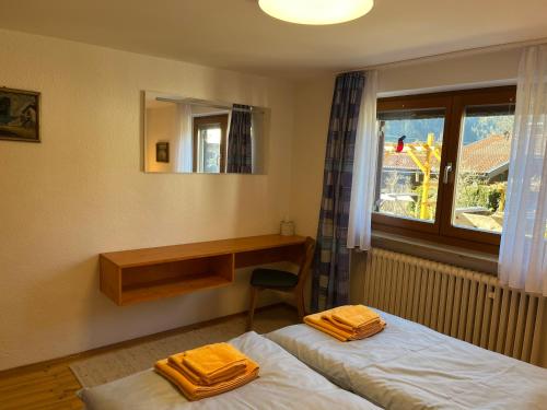 a room with two beds and a desk and a window at Landhaus Renata Bayrischzell in Bayrischzell