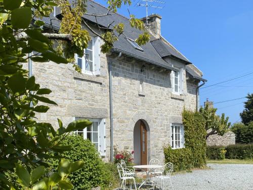 a stone house with a table and chairs in front of it at Maison de famille chaleureuse, plage à pied in Saint-Cast-le-Guildo