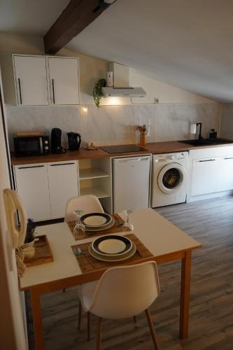 a kitchen with a table and chairs and a kitchen with a washing machine at Appartement Cime - Confort & Charme in Saint-Gaudens