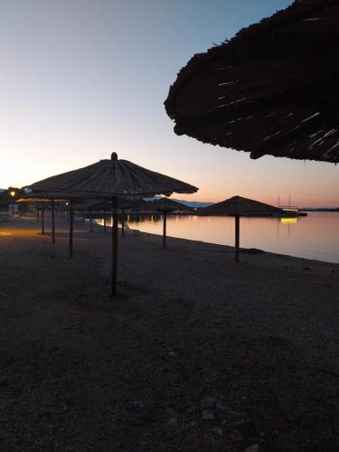 a group of umbrellas on a beach at sunset at Apartments Filip & Nina in Vir