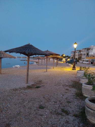 a beach with umbrellas on the beach at night at Apartments Filip & Nina in Vir