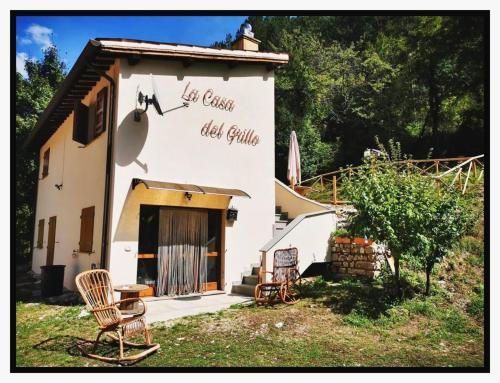 a building with two chairs sitting outside of it at LA CASA DEL GRILLO - Valle del Menotre - Rasiglia in Orsano