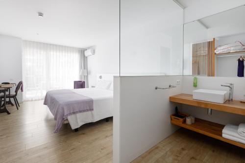 a white bedroom with a bed and a sink at Hotel hcp in Calella de Palafrugell