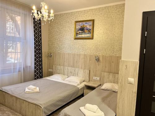 a bedroom with two beds and a chandelier at Апарт-отель "ГАЛАГОВЪ" in Uzhhorod