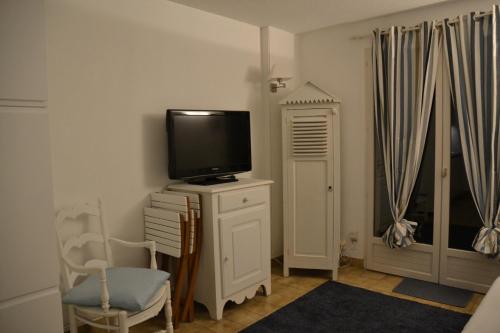 Cette chambre dispose d'une commode avec une chaise et d'une télévision. dans l'établissement Maison à l'Océan, à Batz-sur-Mer