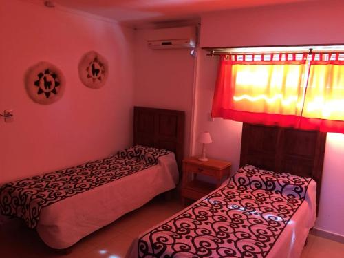 a bedroom with two beds and a window with a curtain at Babel Hostal in Villa María