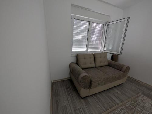 a living room with a couch and two windows at MB Apartment Ferizaj in Ferizaj