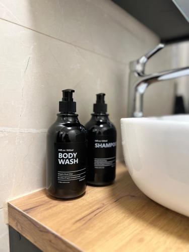 two bottles of body wash sitting on a counter next to a sink at Apartament Rynek 17 in Krosno