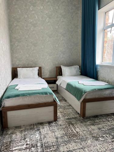 Dos camas una al lado de la otra en una habitación. en Grand Mountains Hotel, en Baysun