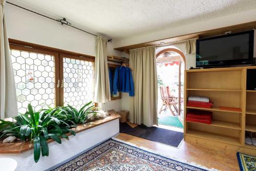 a living room with a tv and some plants at Landhaus Renata Bayrischzell in Bayrischzell