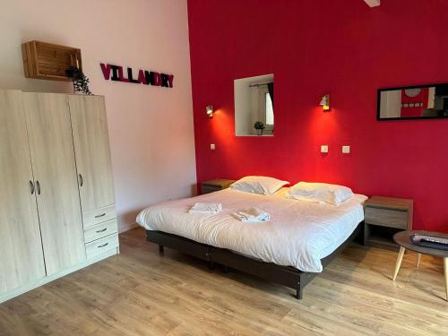 a bedroom with a large bed with a red wall at Studio 2 personnes Villandry avec jardin in Villandry