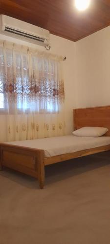 a bedroom with a wooden bed with a window at Kusum villa in Imaduwa