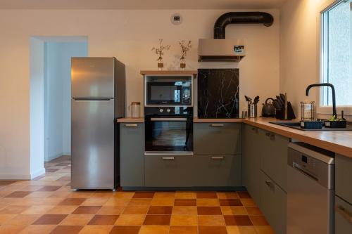 a kitchen with a stainless steel refrigerator and microwave at Le Havre du Lac in Brignemont