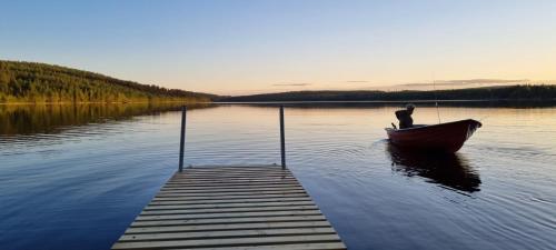 a man in a boat on a lake with a dock at Wild Power Guesthouse in Lycksele