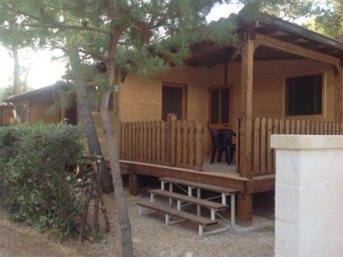 a small wooden cabin with a porch and a table at Camping Villaggio Pineta Al Mare in Specchiolla 