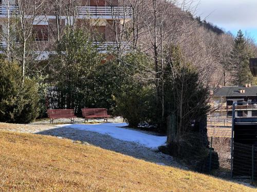 a park with two benches and trees and snow at Il nido d'Ala in Ala di Stura