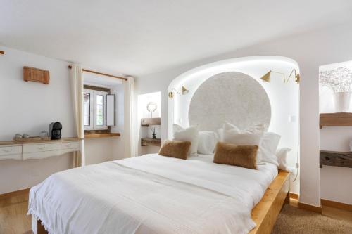 a white bedroom with a large white bed with an arch at Quinta da Relva - Soulful House in Mafra