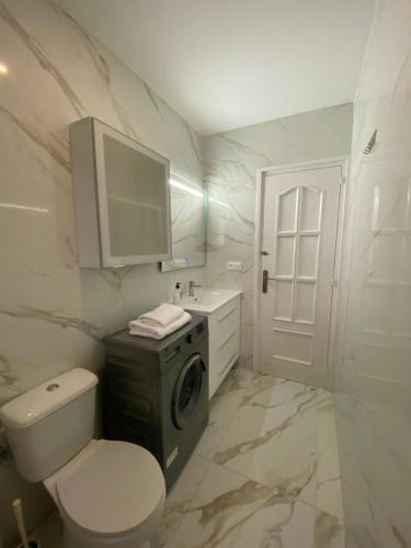 a bathroom with a toilet and a sink and a washing machine at REQUESENS Playa in Empuriabrava