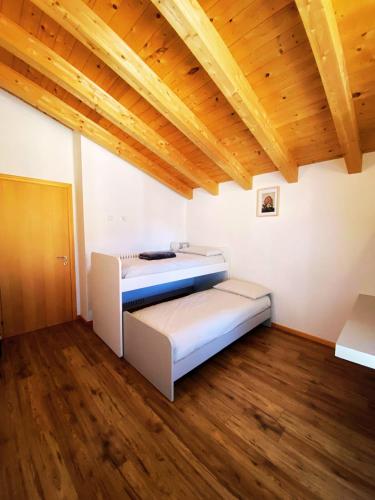 two beds in a room with a wooden ceiling at Ca' Berti Teglio in Teglio