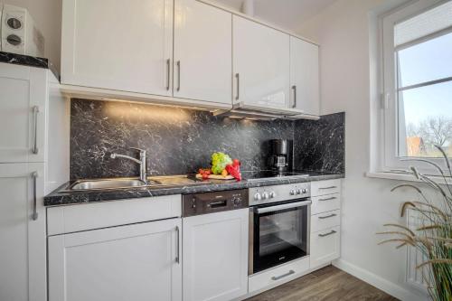 a kitchen with white cabinets and a sink at "Landhaus Voss" Typ 2 Nr8 in Staberdorf