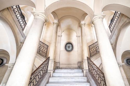 a staircase in a building with a clock on the wall at Palazzo Bicocca Rooms in Catania