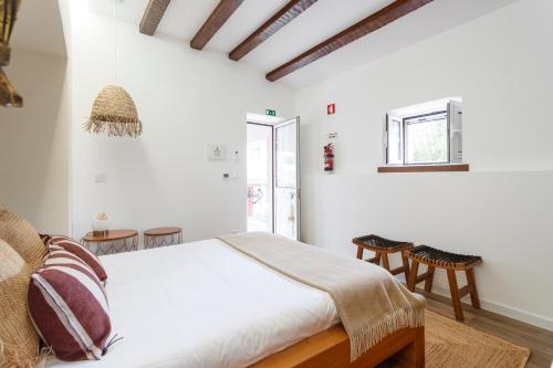 a bedroom with white walls and a bed and chairs at Quinta da Relva - Soulful House in Mafra