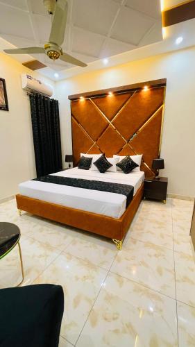 a bedroom with a large bed with a wooden headboard at Holiday Guest House Lahore in Lahore