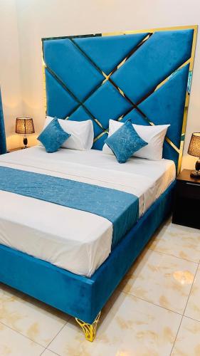 a bed with blue and white pillows on it at Holiday Guest House Lahore in Lahore