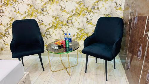 two black chairs sitting next to a glass table at Holiday Guest House Lahore in Lahore